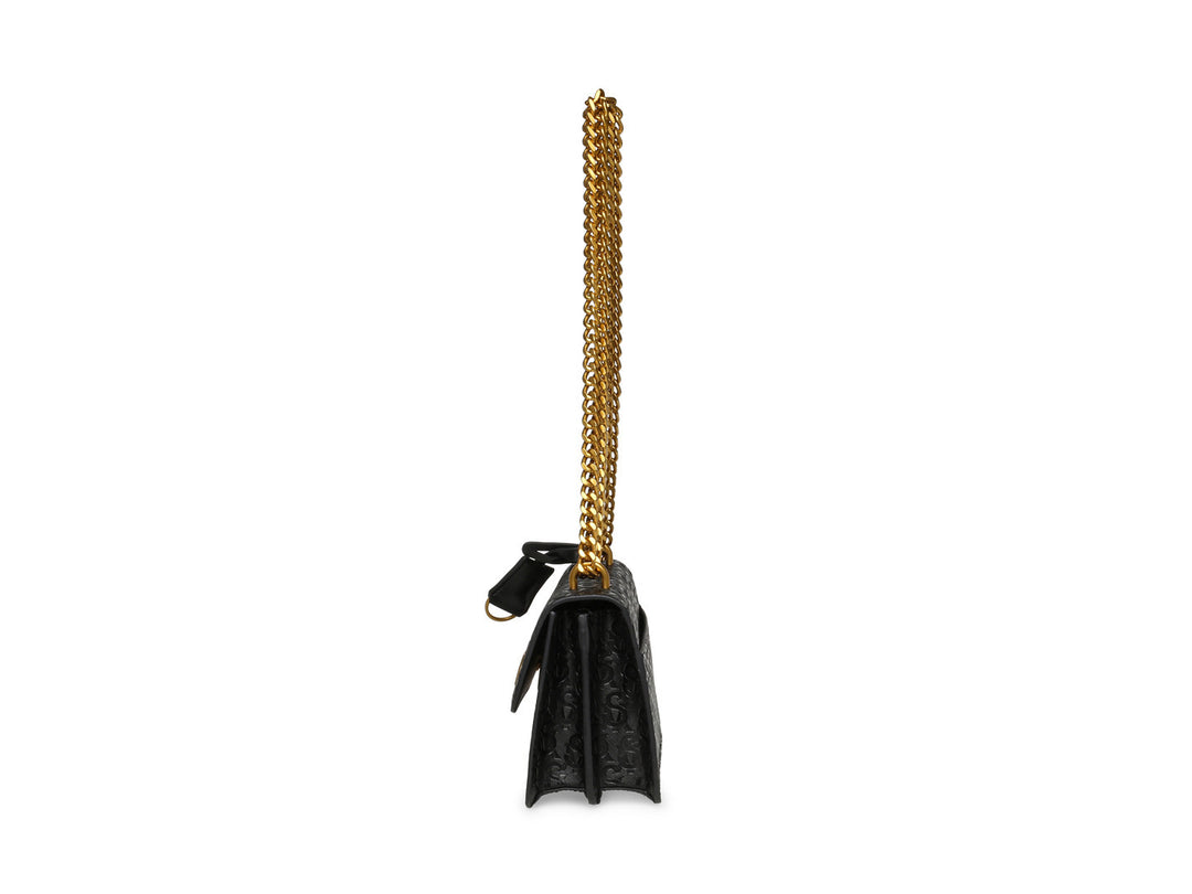 Bolso pequeño negro con acabado brillante y cadena dorada de la marca Steve Madden.