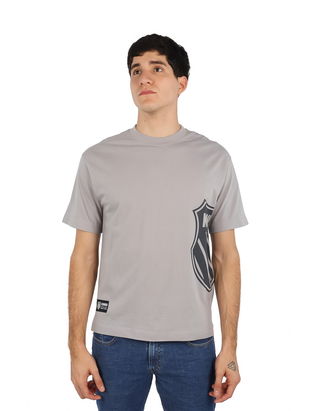 Hombre vistiendo playera gris de manga corta K-Swiss con estampado lateral y cuello redondo.