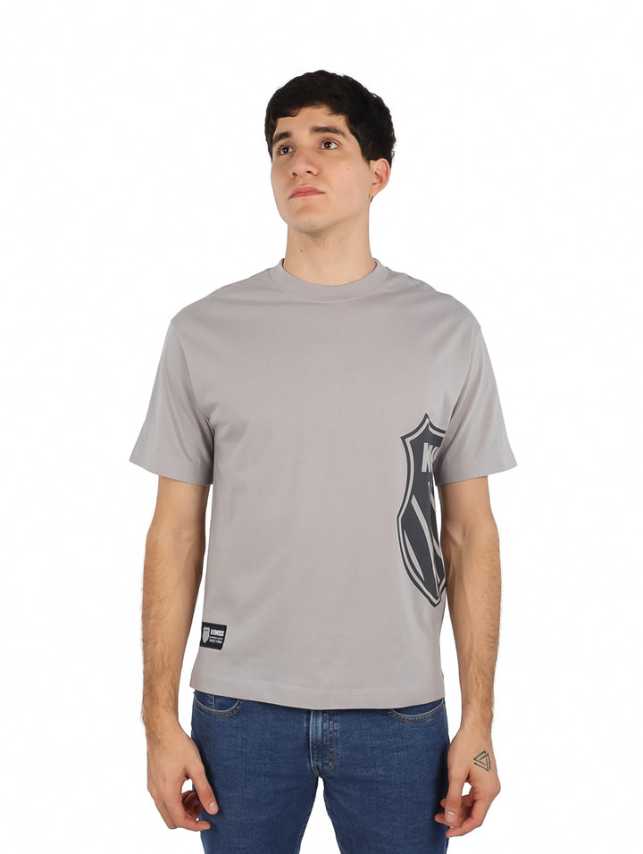 Hombre vistiendo playera gris de manga corta K-Swiss con estampado lateral y cuello redondo.