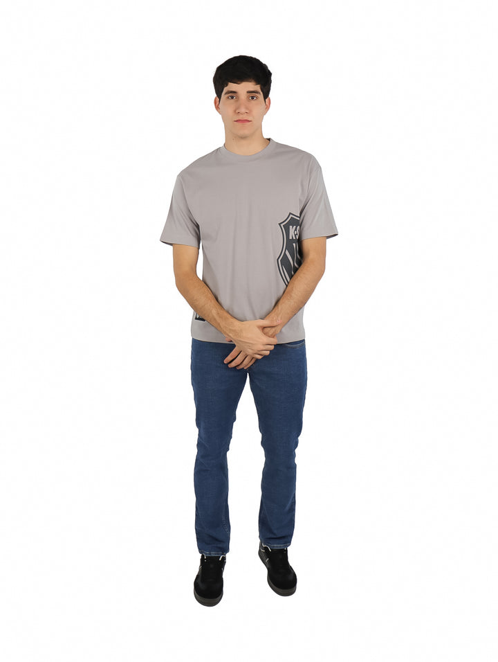 Hombre vistiendo playera gris de manga corta K-Swiss con estampado lateral y cuello redondo.