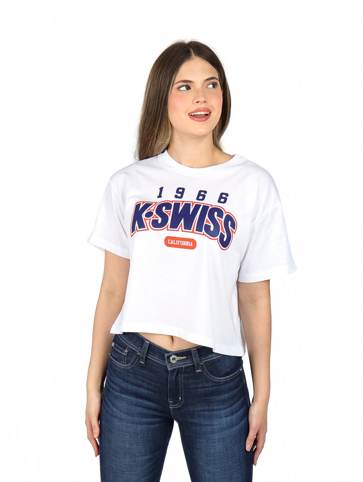 Mujer vistiendo playera blanca crop top de manga corta con logotipo de K-Swiss en el pecho.