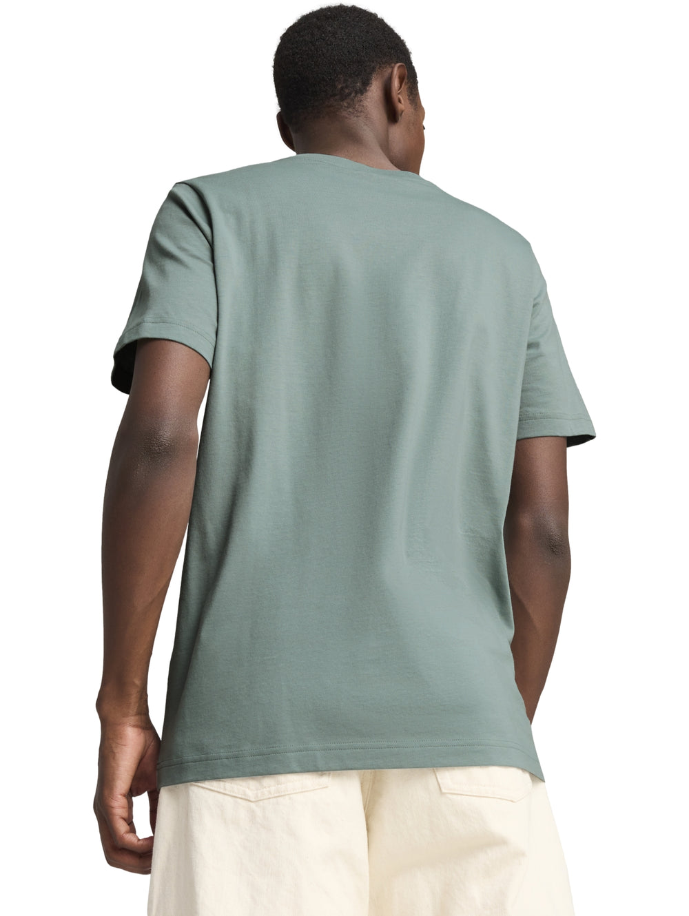 Hombre vistiendo camiseta PUMA color verde con gráfico frontal y pantalones color crema.