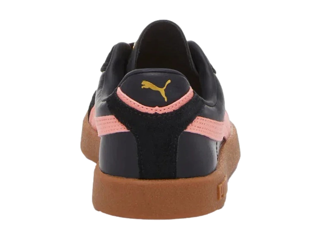 Tenis PUMA negros con franja rosa lateral y suela de goma marrón.