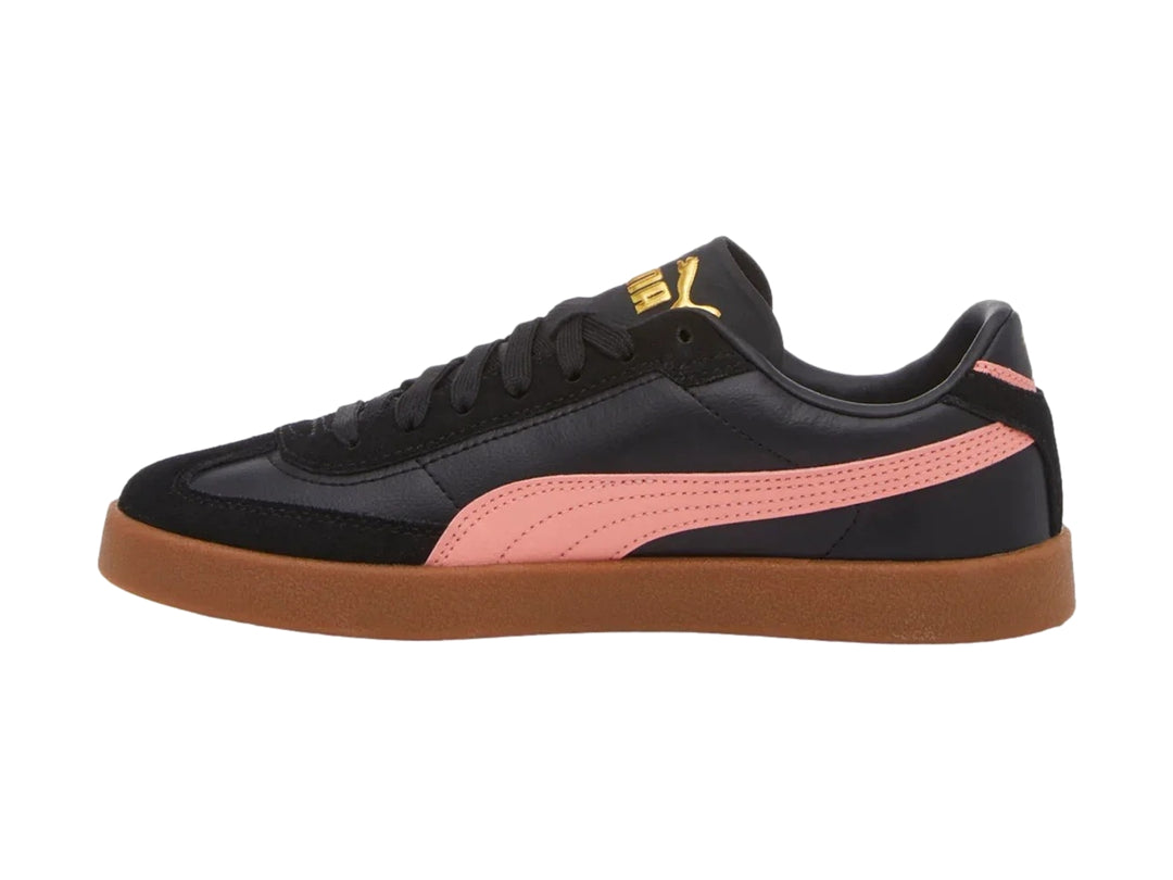 Tenis PUMA negros con franja rosa lateral y suela de goma marrón.