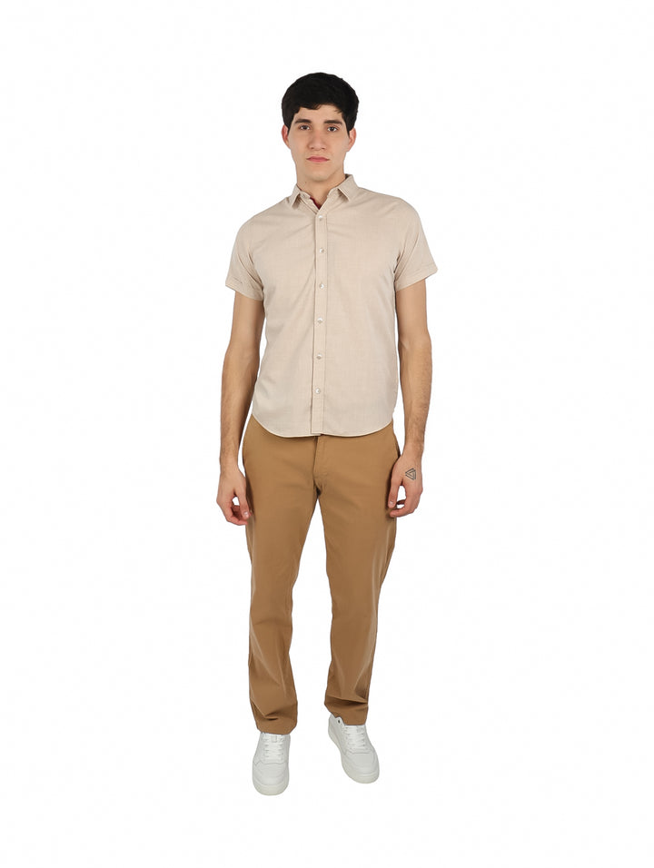 Hombre vistiendo una camisa de manga corta color beige con botones frontales y cuello.