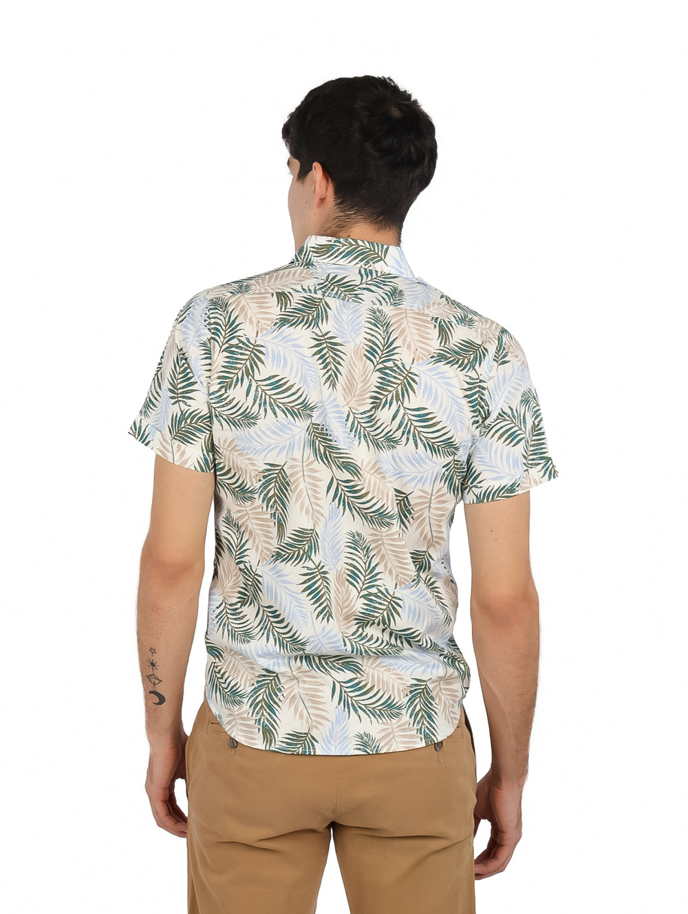Hombre vistiendo camisa de manga corta color hueso con estampado de hojas en tonos verdes y azules.