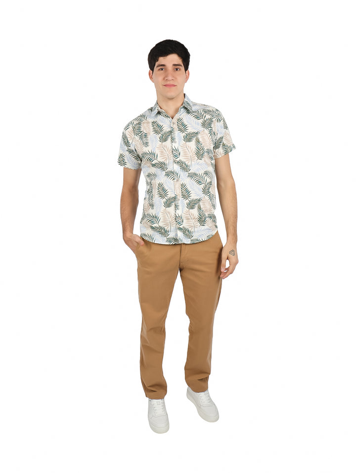 Hombre vistiendo camisa de manga corta color hueso con estampado de hojas en tonos verdes y azules.
