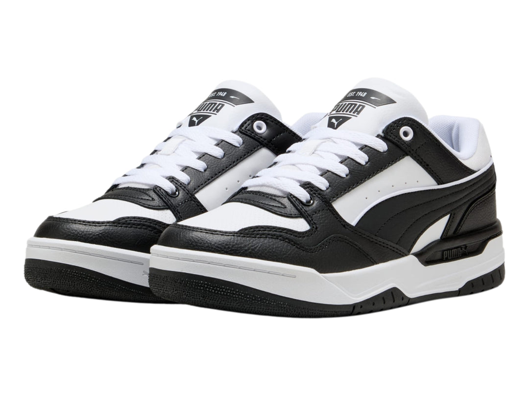 Tenis PUMA Rebound Retro en colores blanco y negro con suela blanca y detalles negros.