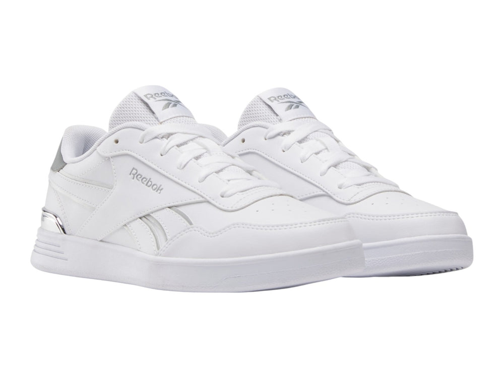 Tenis Reebok blancos de corte bajo con detalles plateados y suela blanca.