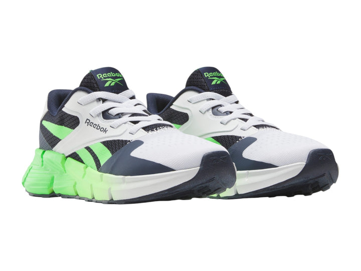 Tenis deportivos Reebok blancos con detalles en azul marino y suela verde neón.