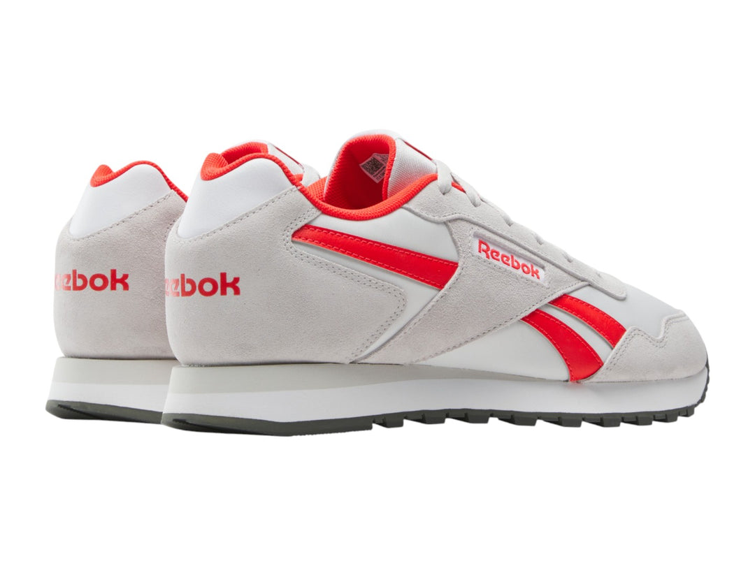 Tenis deportivos Reebok en color blanco con detalles en rojo y suela blanca.