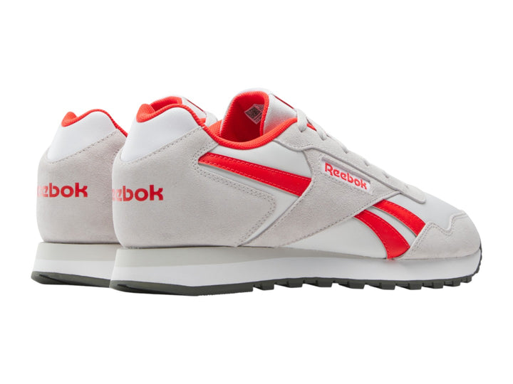Tenis deportivos Reebok en color blanco con detalles en rojo y suela blanca.