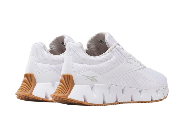 Tenis deportivos Reebok Zig Dynamica en color blanco con suela blanca y base café.