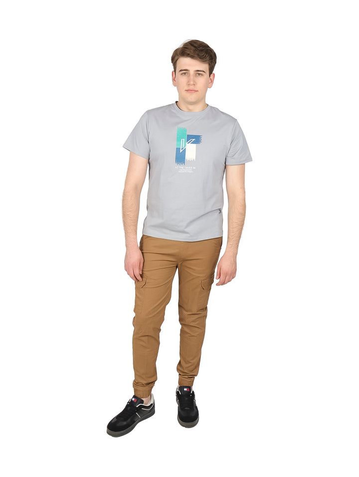 Hombre vistiendo una playera gris de manga corta con un estampado gráfico colorido en el pecho.