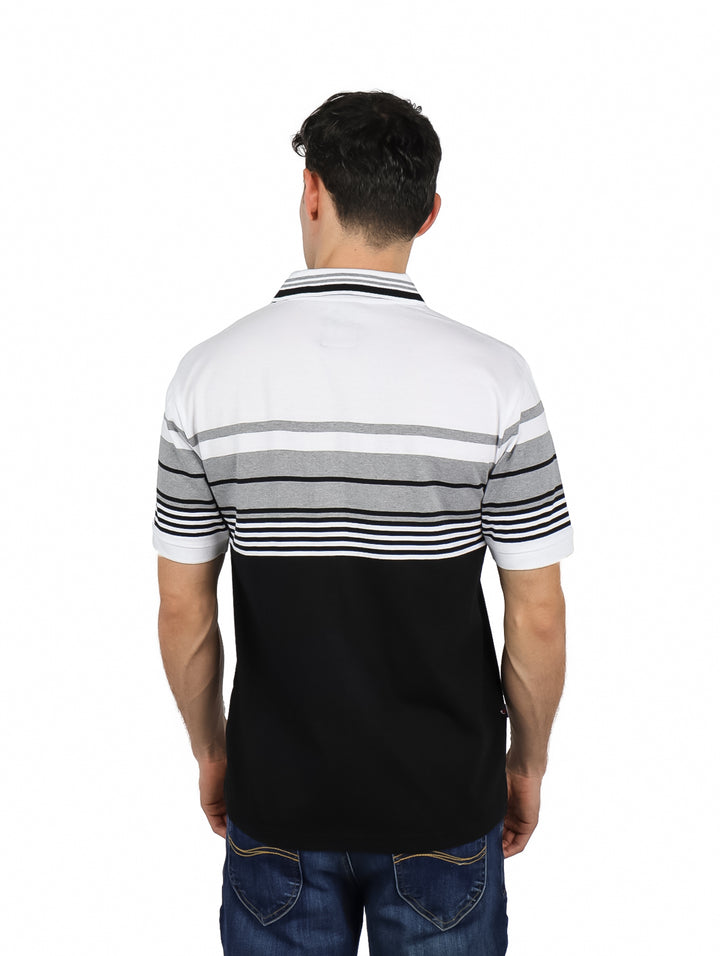 Hombre vistiendo playera polo de manga corta con diseño de bloques de color blanco, gris y negro.