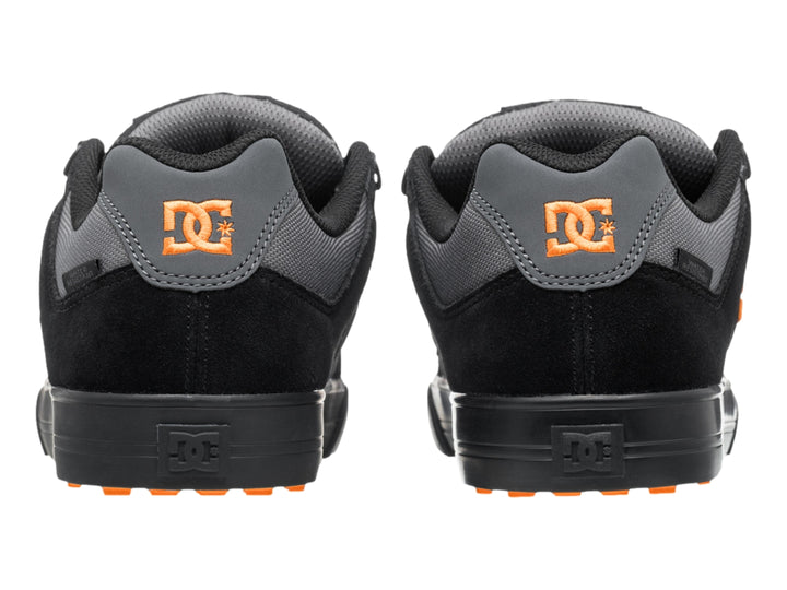 Tenis DC Shoes color negro y gris con logotipo naranja y suela negra, vista lateral.