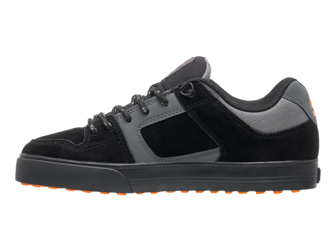 Tenis DC Shoes color negro y gris con logotipo naranja y suela negra, vista lateral.