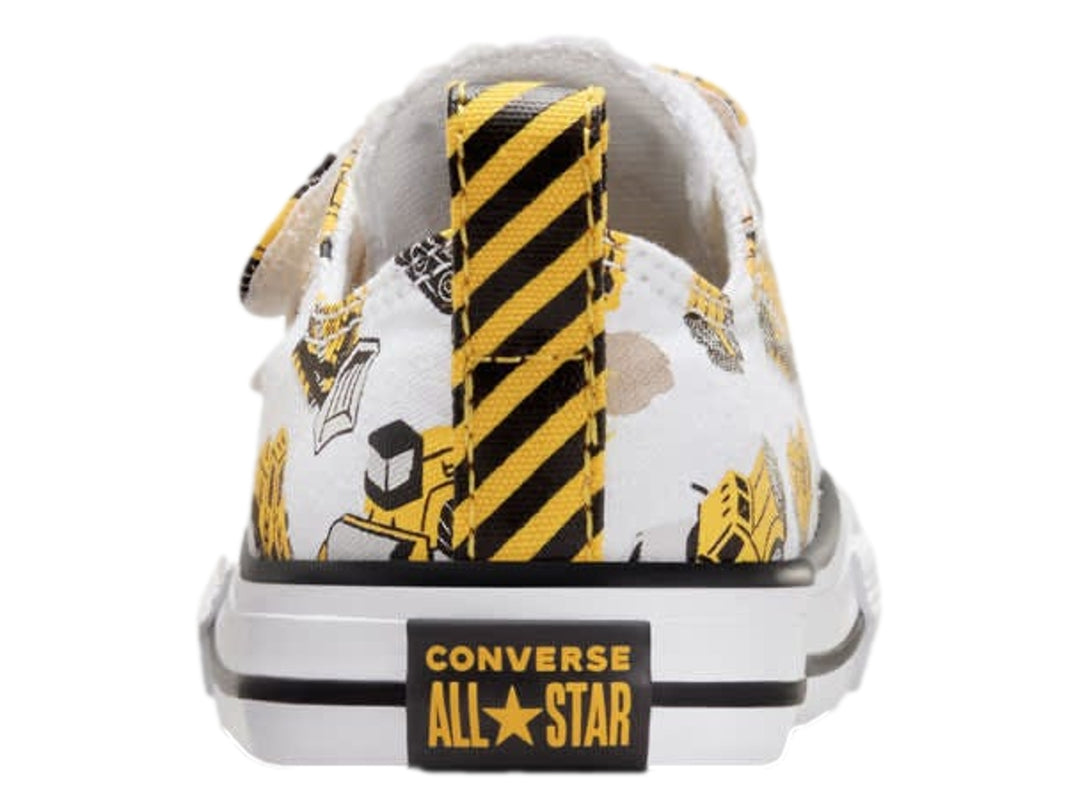 Tenis Converse blancos con estampado de camiones de construcción amarillos y cierres de velcro.