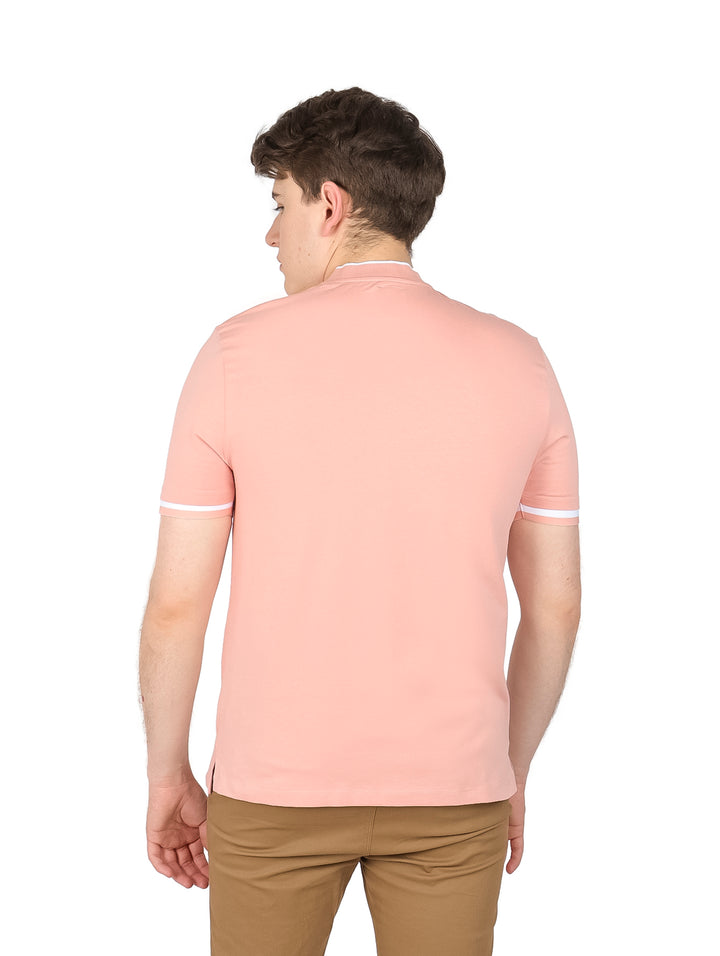 Hombre vistiendo playera rosa de manga corta con cuello Henley y detalles blancos en los bordes de las mangas.
