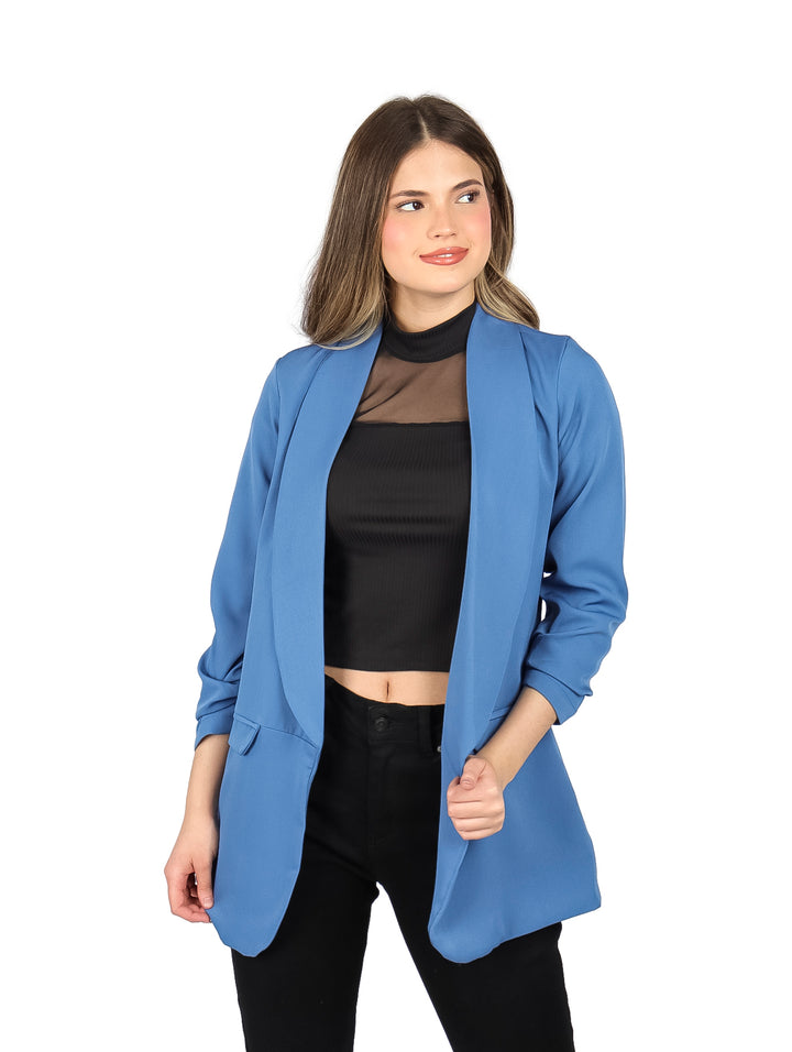 Mujer vistiendo un saco abierto de color azul plumbago con blusa y pantalones negros.