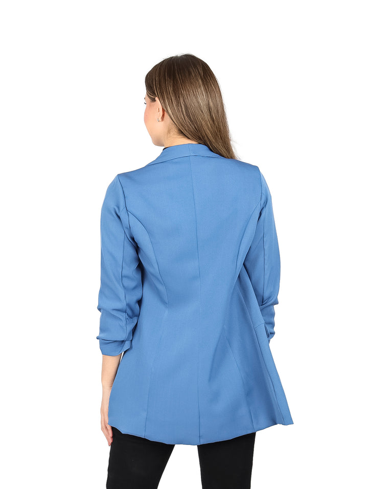 Mujer vistiendo un saco abierto de color azul plumbago con blusa y pantalones negros.
