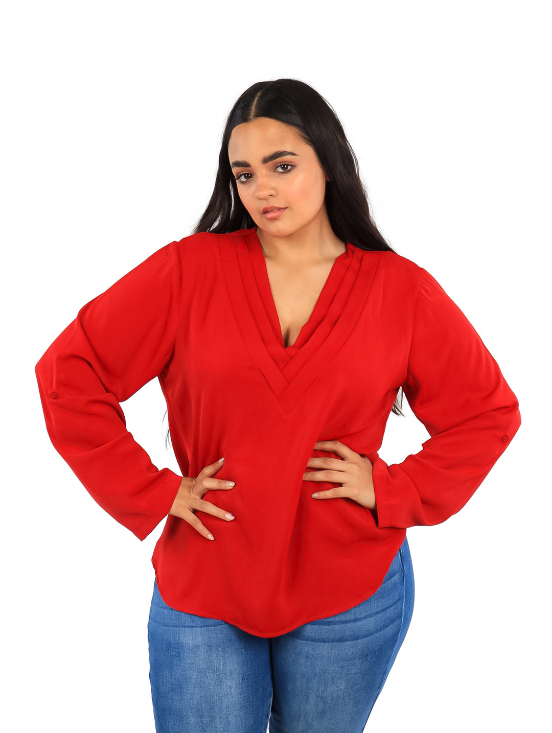 Mujer vistiendo una blusa roja de manga larga con cuello en V y pantalones azules.