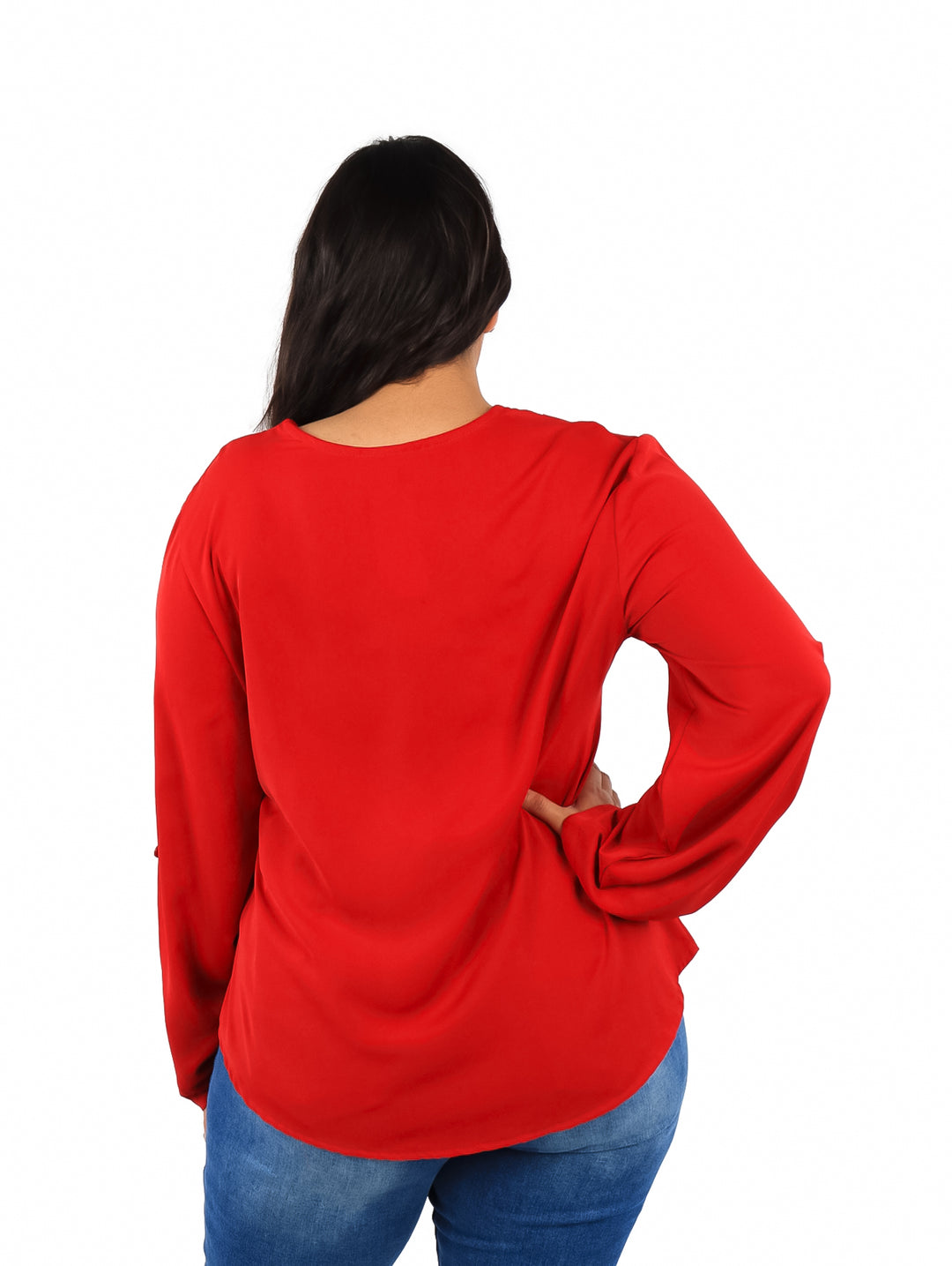 Mujer vistiendo una blusa roja de manga larga con cuello en V y pantalones azules.
