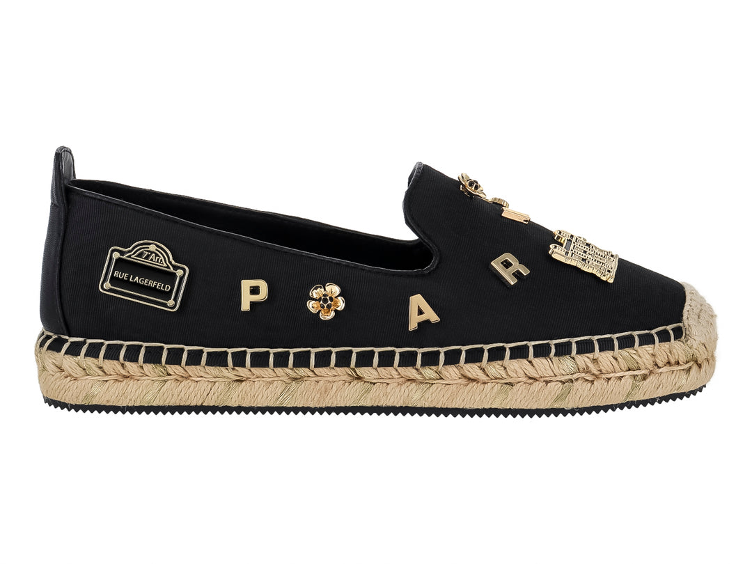 Zapato plano tipo alpargata negro con suela de yute y pines metálicos dorados.