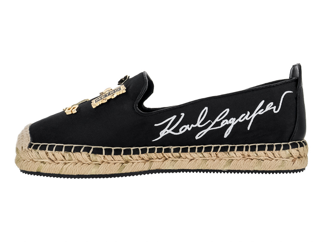Zapato plano tipo alpargata negro con suela de yute y pines metálicos dorados.
