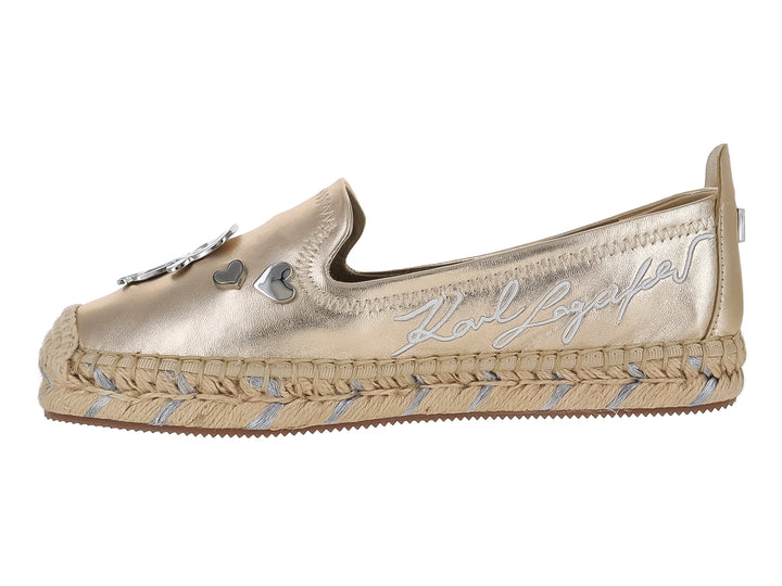Zapato plano tipo alpargata color dorado metálico con detalles decorativos y suela trenzada.