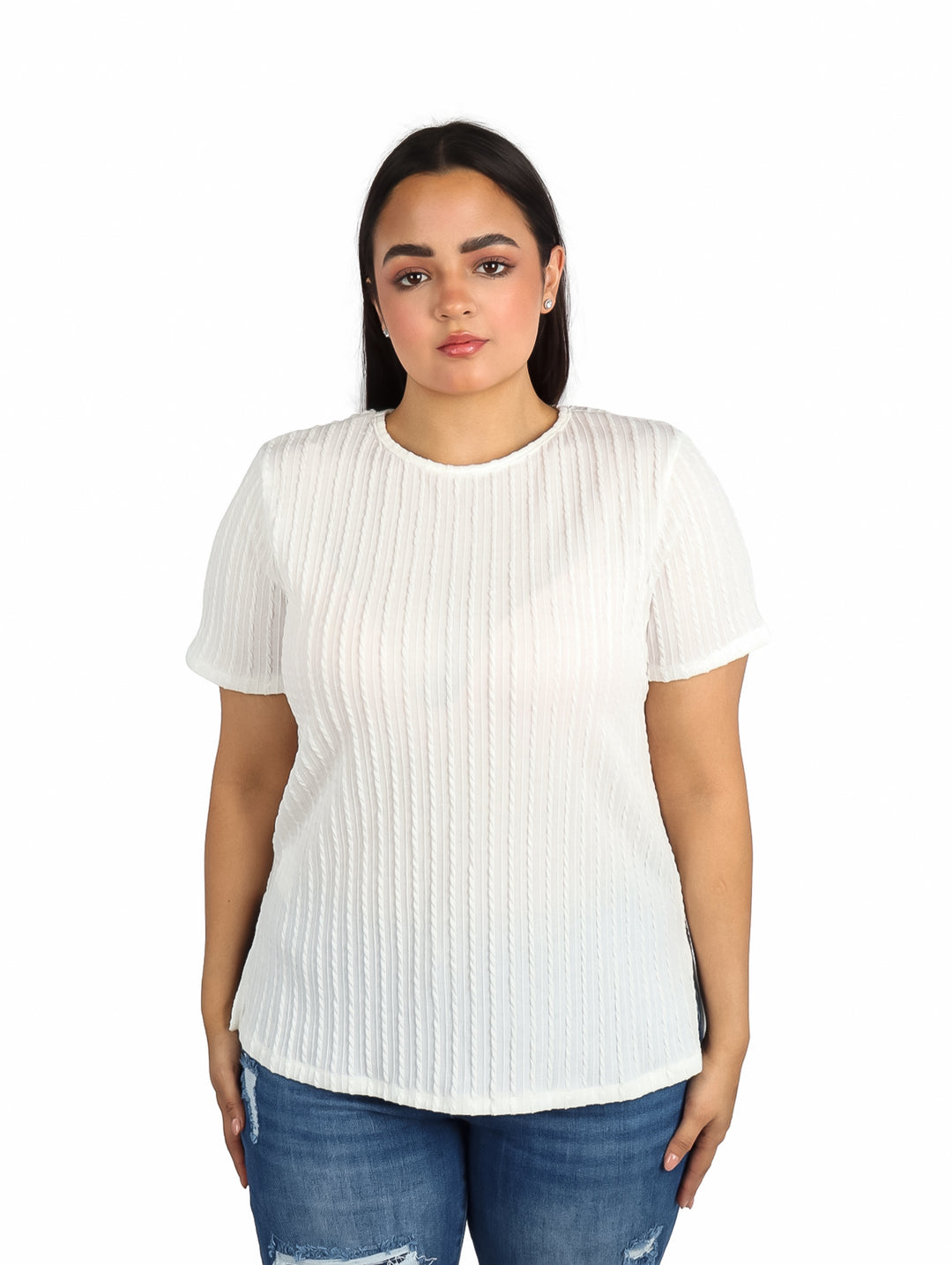 Mujer vistiendo una blusa blanca de manga corta con textura plisada y jeans azules.