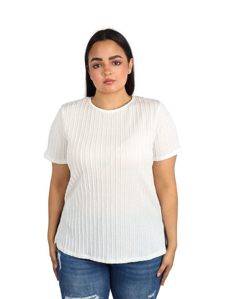 Mujer vistiendo una blusa blanca de manga corta con textura plisada y jeans azules.