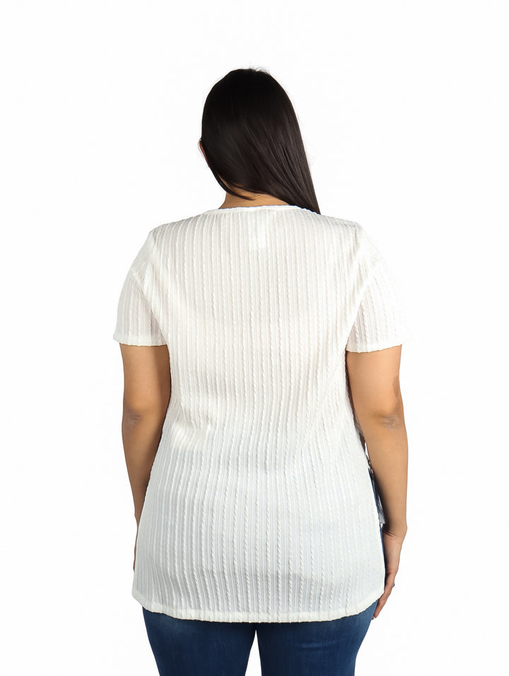 Mujer vistiendo una blusa blanca de manga corta con textura plisada y jeans azules.