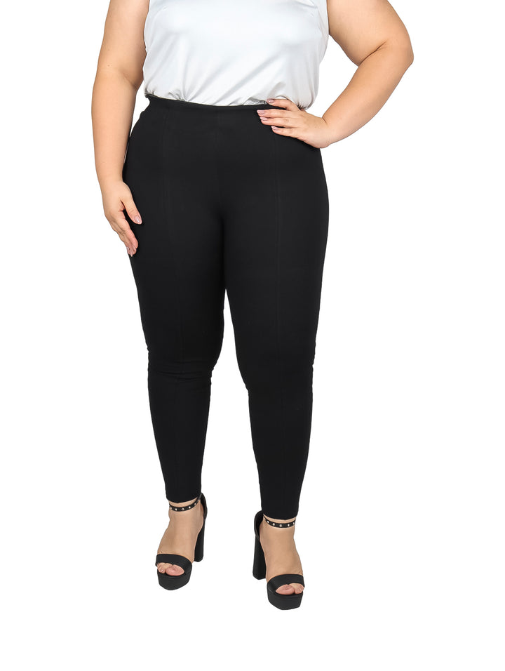 Mujer vistiendo pantalón negro ajustado de cintura alta y blusa blanca.