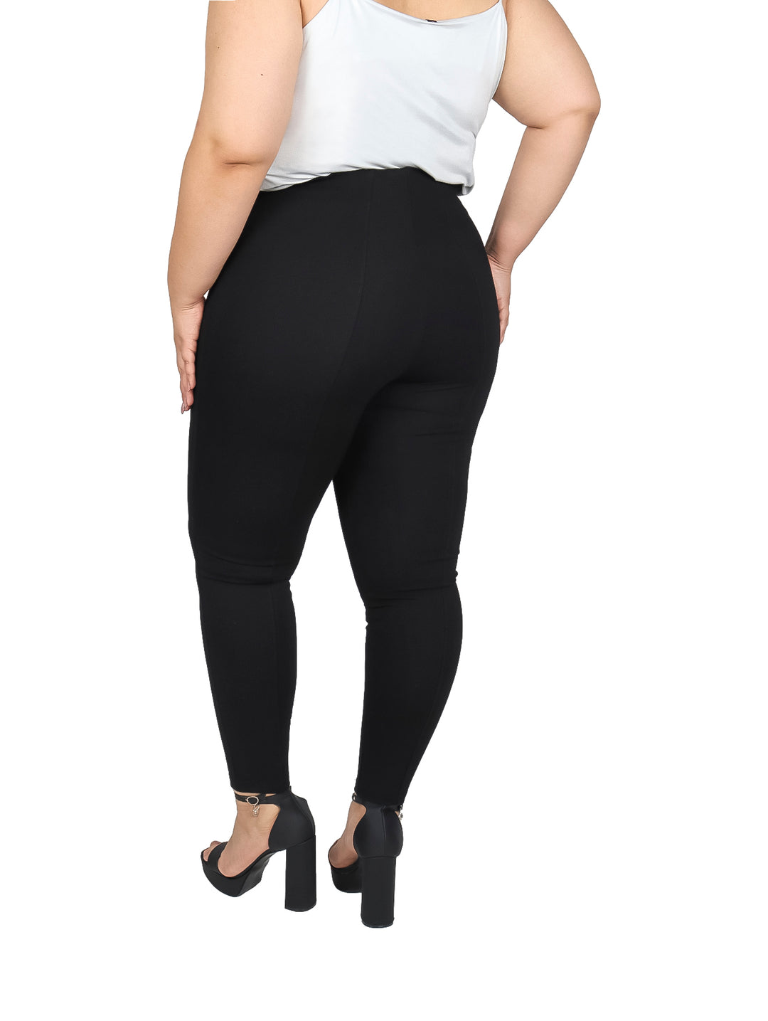Mujer vistiendo pantalón negro ajustado de cintura alta y blusa blanca.