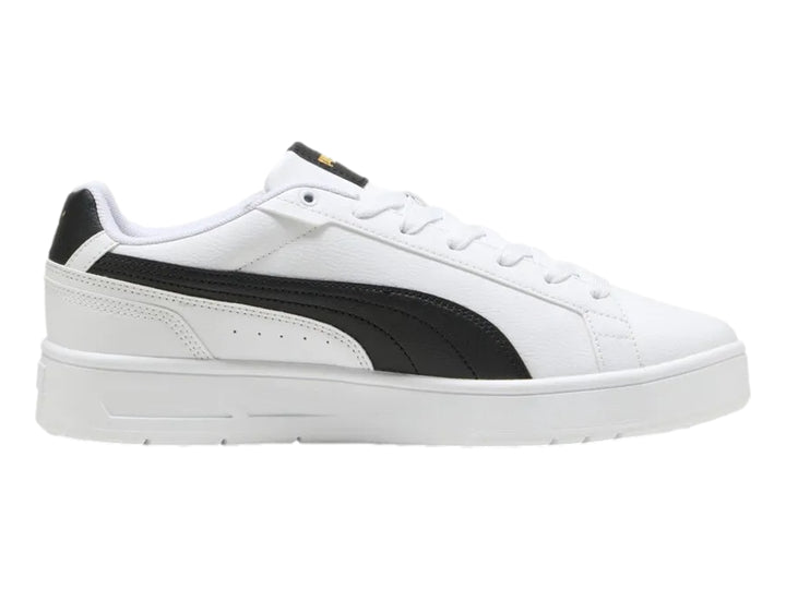 Tenis PUMA blancos con franja lateral negra y detalles dorados en la lengüeta.