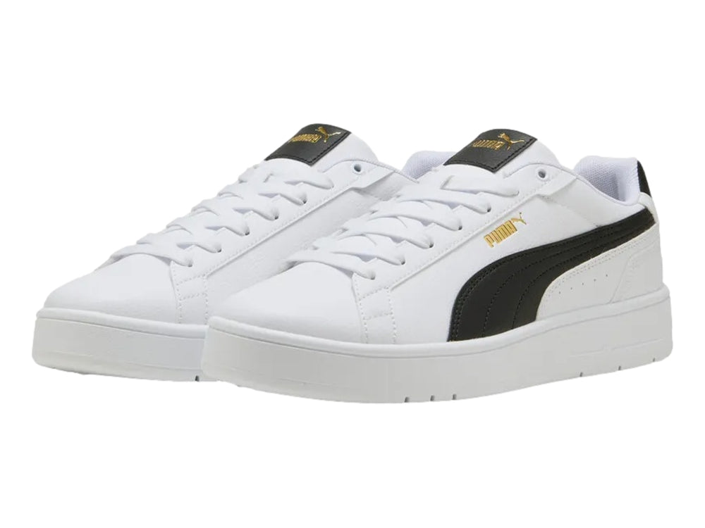 Tenis PUMA blancos con franja lateral negra y detalles dorados en la lengüeta.