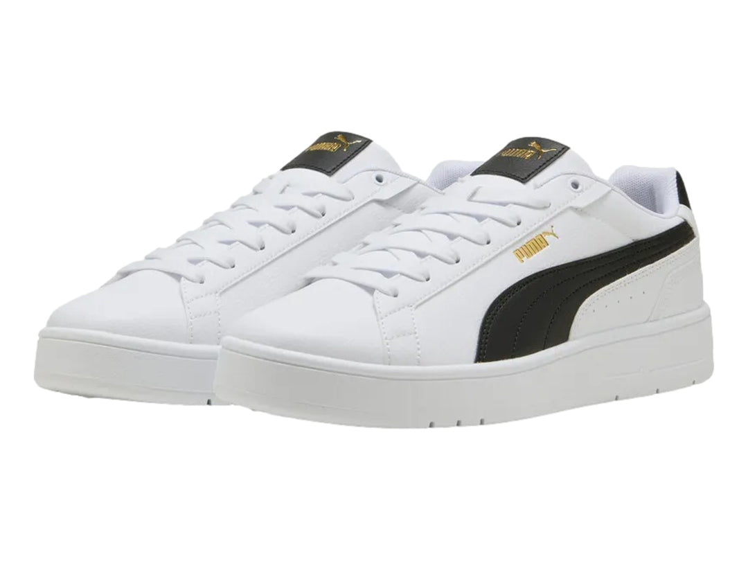 Tenis PUMA blancos con franja lateral negra y detalles dorados en la lengüeta.