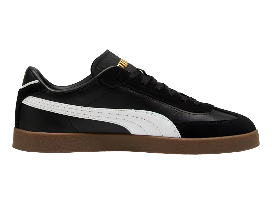 Tenis PUMA negros con franja blanca lateral y suela de goma color café.