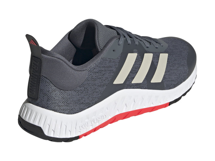 Tenis deportivos Adidas color gris con franjas blancas y suela blanca con detalle rojo en la base.