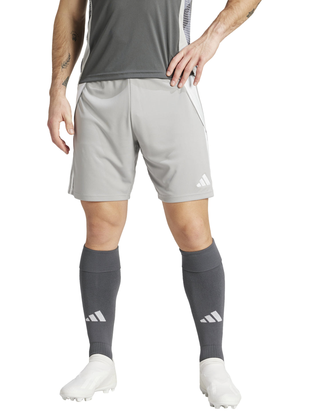 Hombre vistiendo shorts deportivos Adidas color gris con detalles blancos laterales.