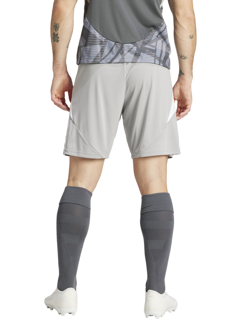 Hombre vistiendo shorts deportivos Adidas color gris con detalles blancos laterales.