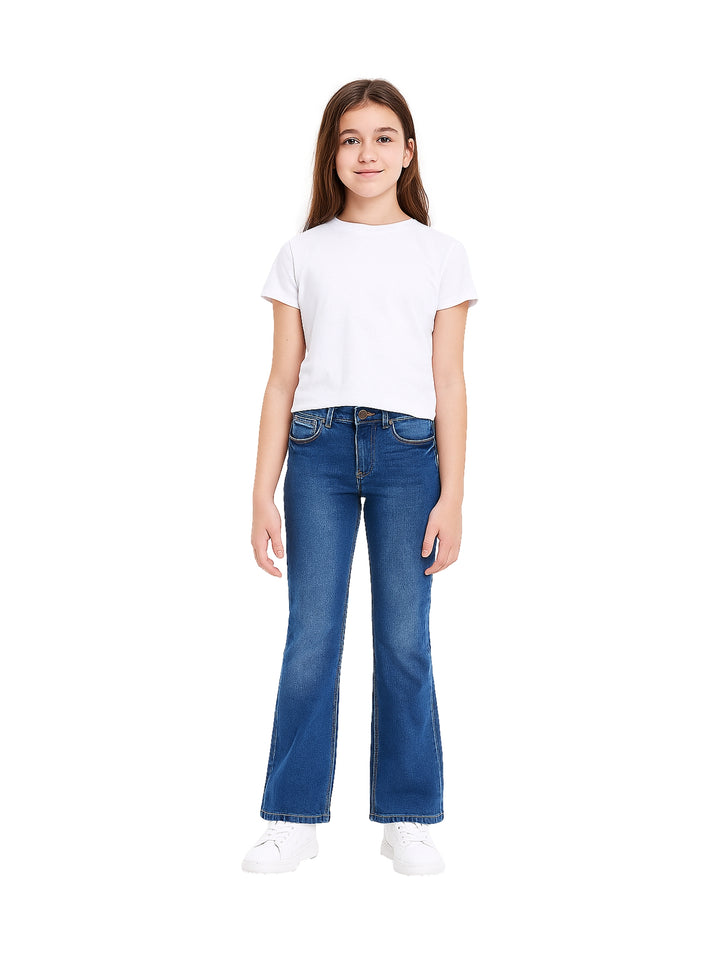 Niña vistiendo pantalón de mezclilla azul estilo campana y camiseta blanca sobre fondo blanco.