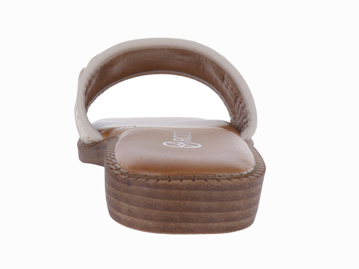Sandalia plana color beige para mujer con banda tejida y hebilla metálica dorada.