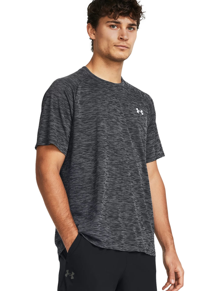 Hombre vistiendo playera deportiva Under Armour de color gris jaspeado con manga corta y cuello redondo.
