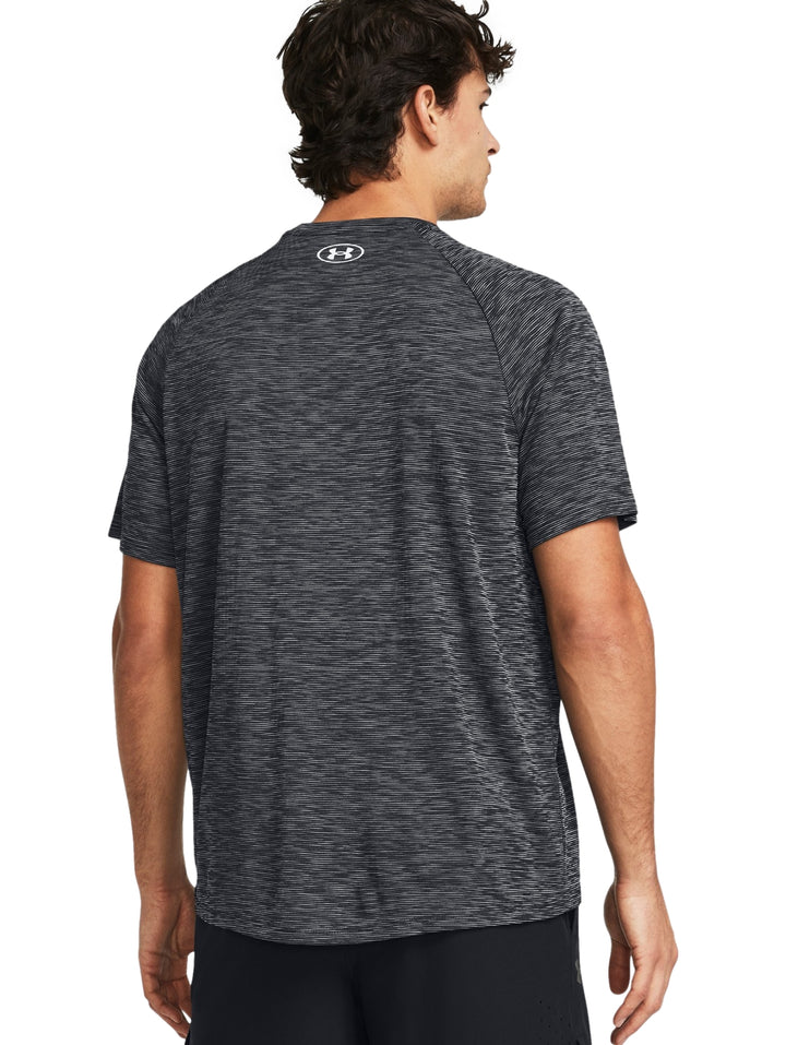 Hombre vistiendo playera deportiva Under Armour de color gris jaspeado con manga corta y cuello redondo.