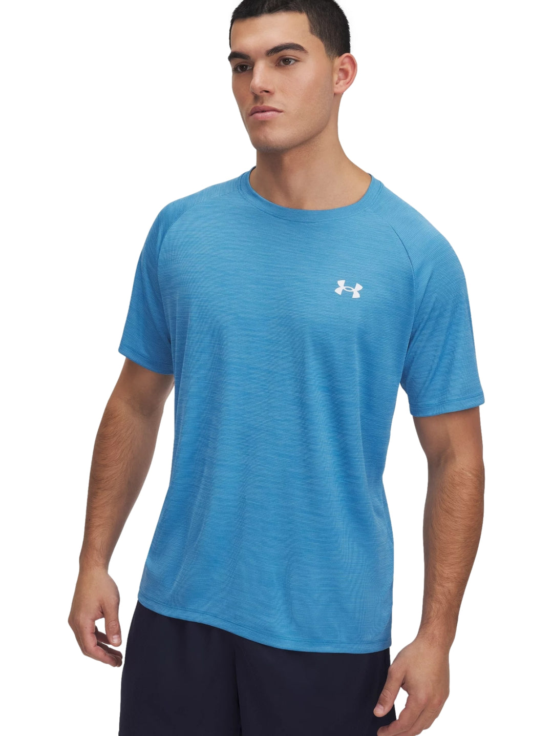 Hombre vistiendo una camiseta deportiva Under Armour de color azul ether blue con textura y logo blanco en el pecho.