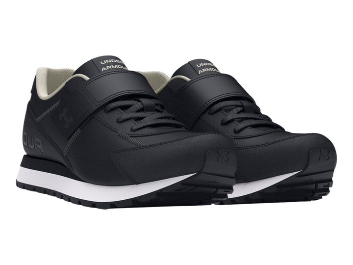 Tenis deportivos Under Armour color negro con suela blanca y cierre de cinta de velcro para niño.