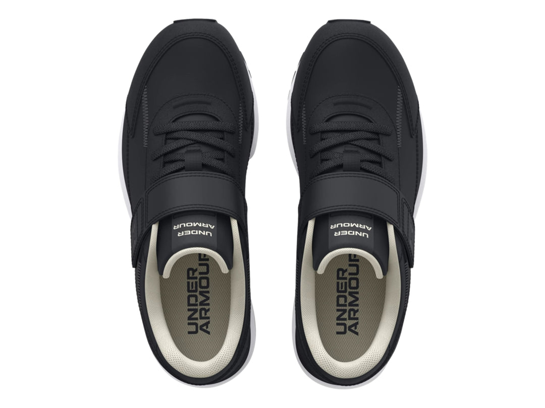 Tenis deportivos Under Armour color negro con suela blanca y cierre de cinta de velcro para niño.