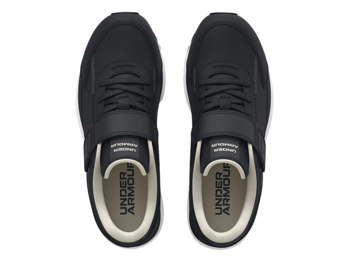 Tenis deportivos Under Armour color negro con suela blanca y cierre de cinta de velcro para niño.
